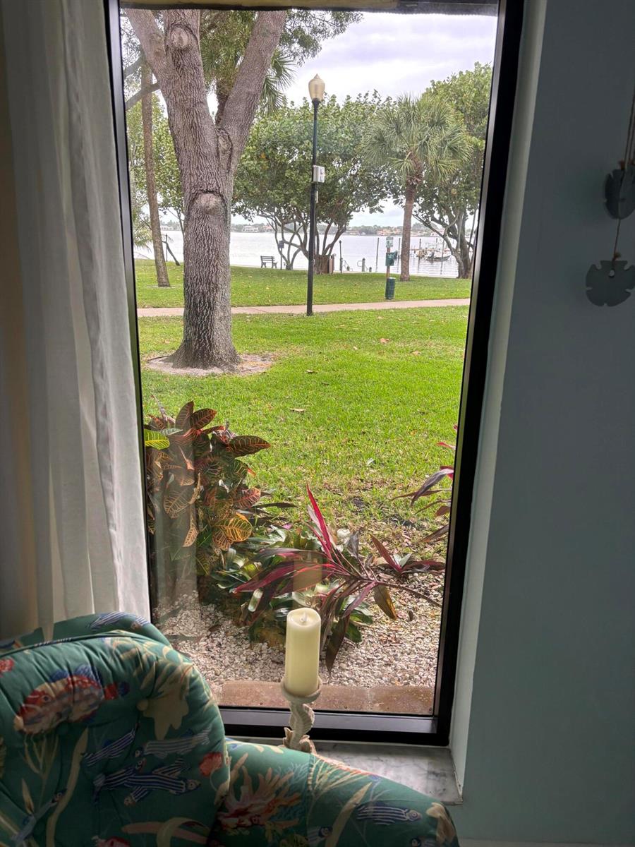 A view through a window shows a grassy lawn, trees, and a waterfront scene — 825 Center Street # 21b, Jupiter FL 33458, JUPITER, FL