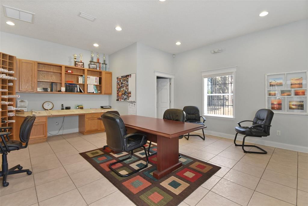 An office room features a wooden desk, black chairs, built-in cabinets, and a colorful area rug — 2071 DOBBS ROAD, ST AUGUSTINE, FL