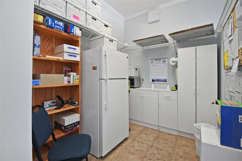 A small utility room features a white refrigerator, wooden shelving, white cabinets, and tile flooring — 2071 DOBBS ROAD, ST AUGUSTINE, FL