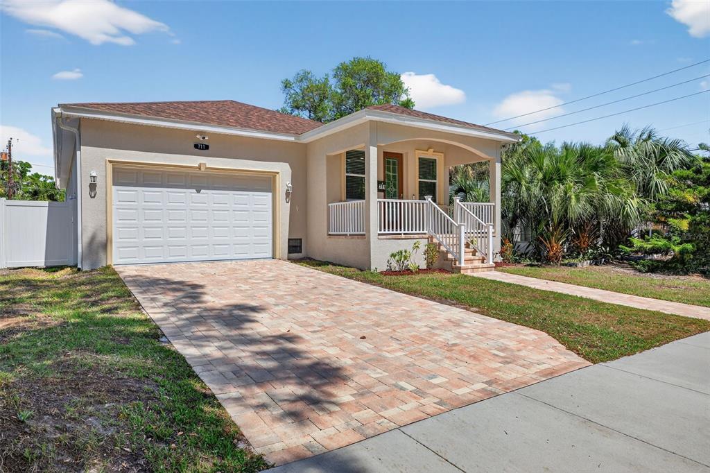 A single-story house with a paved driveway, a white garage door, and a covered porch — 711 28TH AVENUE S, ST PETERSBURG, FL