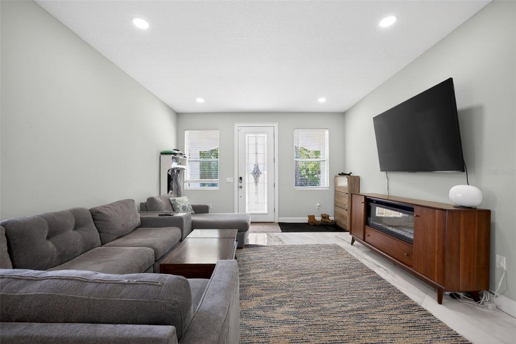 A living room features a grey sectional sofa, a wooden media console, and a front door — 711 28TH AVENUE S, ST PETERSBURG, FL