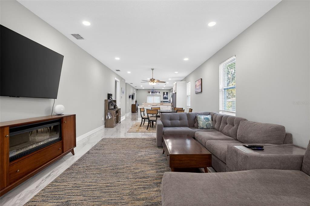 A living room with a gray sectional sofa, fireplace console, and open-concept dining area — 711 28TH AVENUE S, ST PETERSBURG, FL