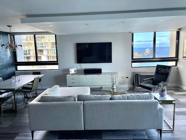 A modern living room features a sectional sofa, a wall-mounted television, and ocean views — 4123 ISLA VERDE AVENUE UNIT 16, CAROLINA, PR