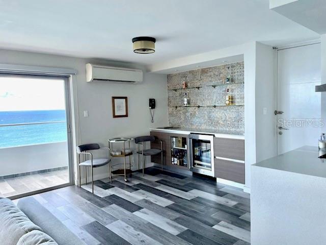 A modern room features a wet bar with glass shelving, wood-look flooring, and a balcony view — 4123 ISLA VERDE AVENUE UNIT 16, CAROLINA, PR