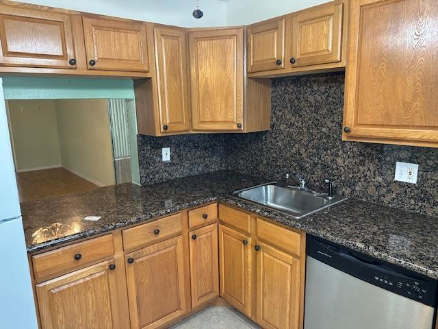 A kitchen features oak cabinets, dark granite countertops, a stainless steel sink, and a dishwasher — 7300 NW 5th Court # 101, Margate FL 33063, MARGATE, FL