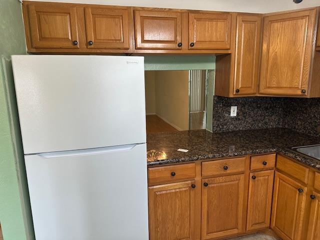 A white refrigerator stands next to wood cabinets and granite countertops in a kitchen — 7300 NW 5th Court # 101, Margate FL 33063, MARGATE, FL