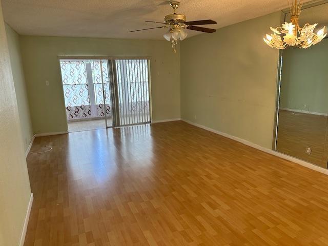 An empty living room with light green walls, wood-look flooring, a ceiling fan, and mirrors — 7300 NW 5th Court # 101, Margate FL 33063, MARGATE, FL
