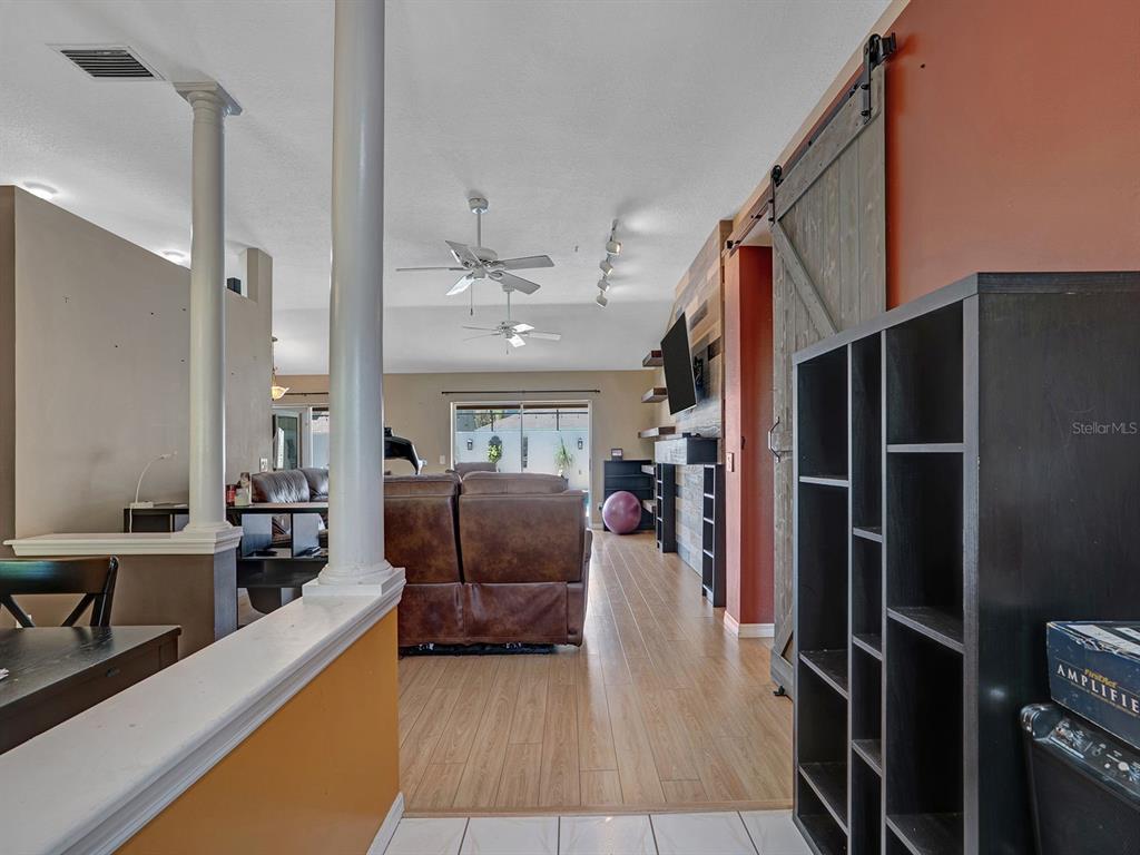 A living room features wood-look flooring, a sliding barn door, and a brown leather sofa — 6310 TURTLE CREEK BOULEVARD, TAMPA, FL
