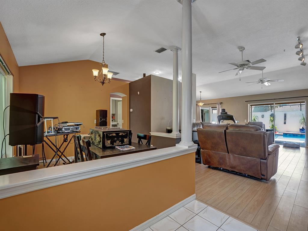 A living room with light wood flooring, a pool view, and a dining area nearby — 6310 TURTLE CREEK BOULEVARD, TAMPA, FL