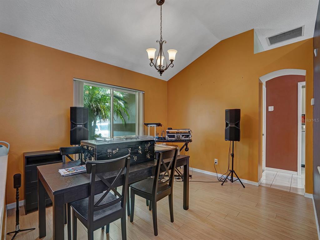 A dining room with orange walls, a chandelier, wood-look flooring, and audio equipment — 6310 TURTLE CREEK BOULEVARD, TAMPA, FL