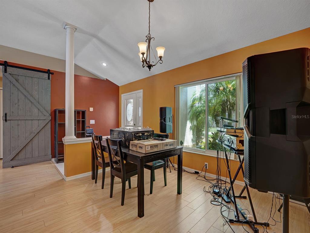A dining room features a vaulted ceiling, a barn door, and audio equipment on stands — 6310 TURTLE CREEK BOULEVARD, TAMPA, FL
