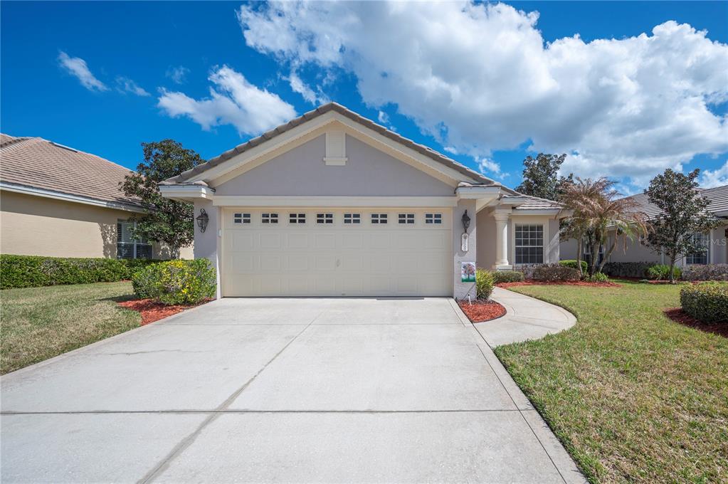 A single-story house with a beige garage door, concrete driveway, and landscaped front yard — 3342 TURNBERRY LANE, LAKELAND, FL