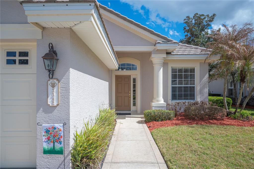 A concrete walkway leads to the front entrance of a single-story house with stucco siding — 3342 TURNBERRY LANE, LAKELAND, FL