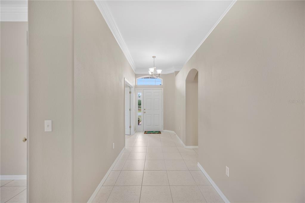 A tiled entryway features a white front door with a transom window and a chandelier — 3342 TURNBERRY LANE, LAKELAND, FL