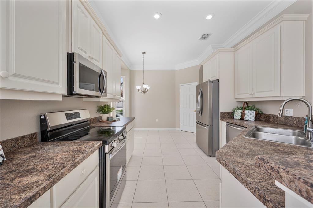 A kitchen with white cabinets, brown laminate countertops, stainless steel appliances, and tile flooring — 3342 TURNBERRY LANE, LAKELAND, FL