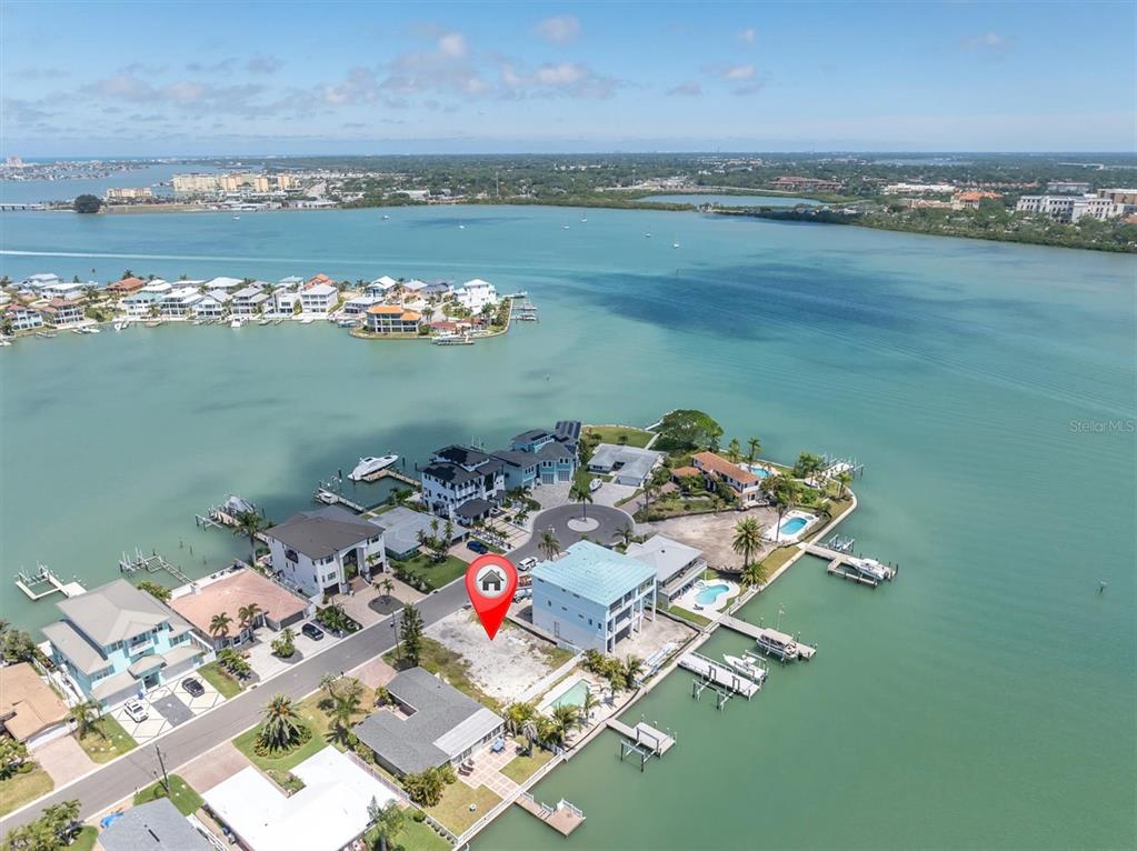 An aerial view shows a vacant waterfront lot marked with a red house icon — 575 CRYSTAL DRIVE, MADEIRA BEACH, FL