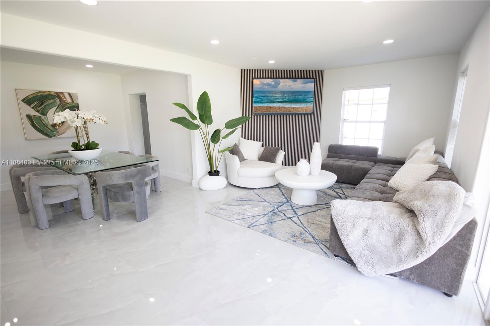 A modern living and dining area features white tile floors, gray furniture, and a television — 1435 Grant St, Hollywood FL 33020, HOLLYWOOD, FL