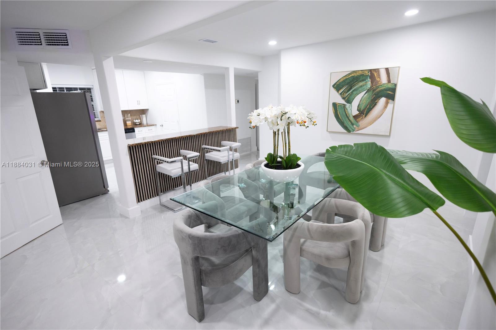 A dining area features a glass table, upholstered chairs, and a slatted breakfast bar — 1435 Grant St, Hollywood FL 33020, HOLLYWOOD, FL