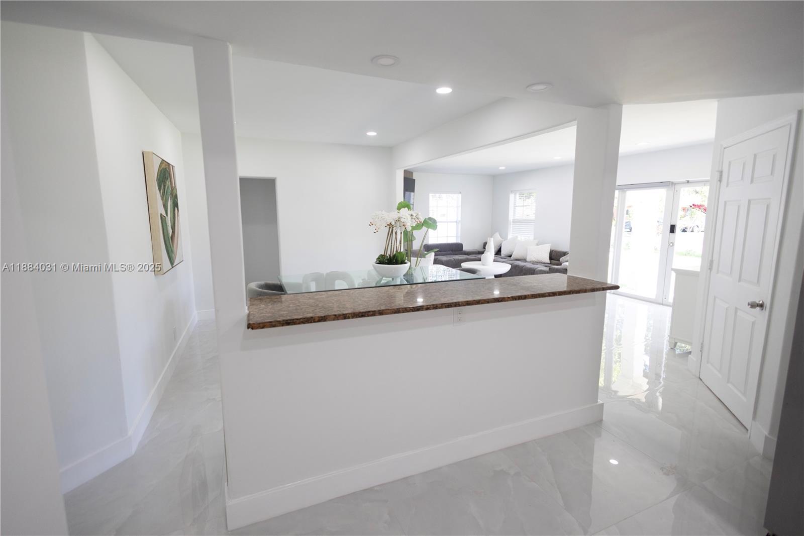 A kitchen pass-through counter with a granite top overlooks a living area with tile floors — 1435 Grant St, Hollywood FL 33020, HOLLYWOOD, FL
