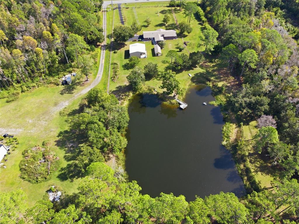 An aerial view shows a house, a detached garage, and a pond on a wooded lot — 9240 MOORE ROAD, LAKELAND, FL