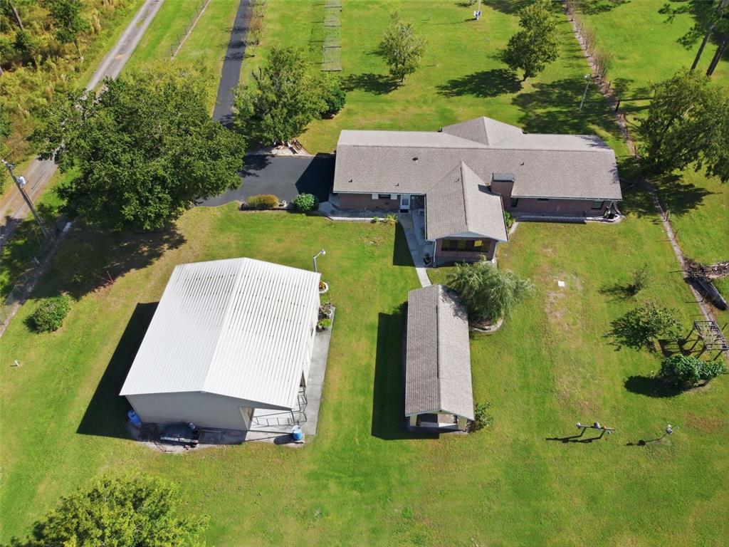 An aerial view shows a house, a detached garage, and a shed on a grassy lot — 9240 MOORE ROAD, LAKELAND, FL