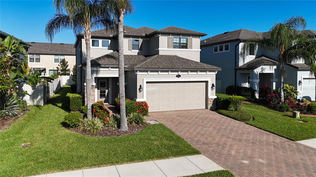 A two-story suburban house features a paved driveway, a two-car garage, and palm trees — 1953 NATURE VIEW DRIVE, LUTZ, FL