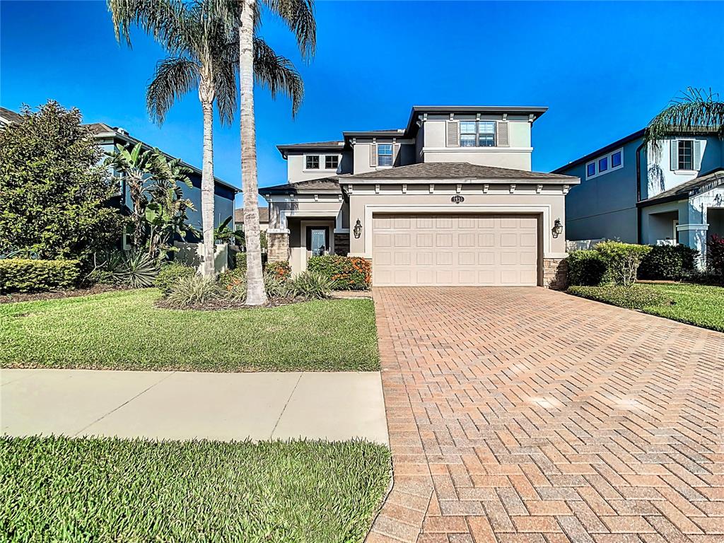 A two-story house with a beige exterior, a brick paver driveway, and a palm tree — 1953 NATURE VIEW DRIVE, LUTZ, FL