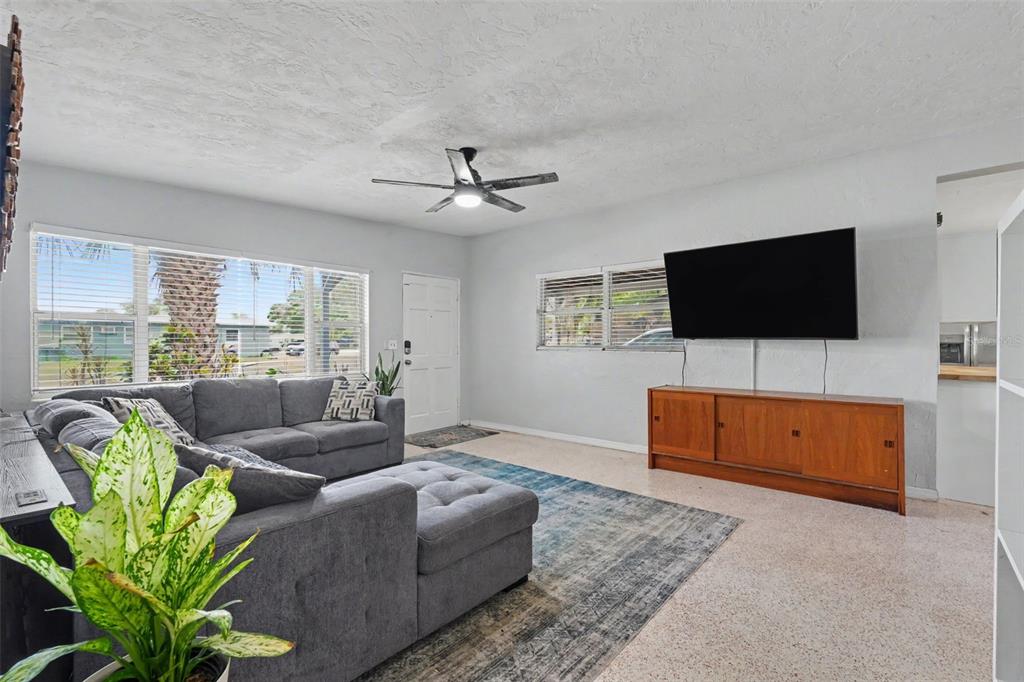 A living room features a gray sectional sofa, a wooden media console, and a ceiling fan — 2270 NOLAN DRIVE, LARGO, FL