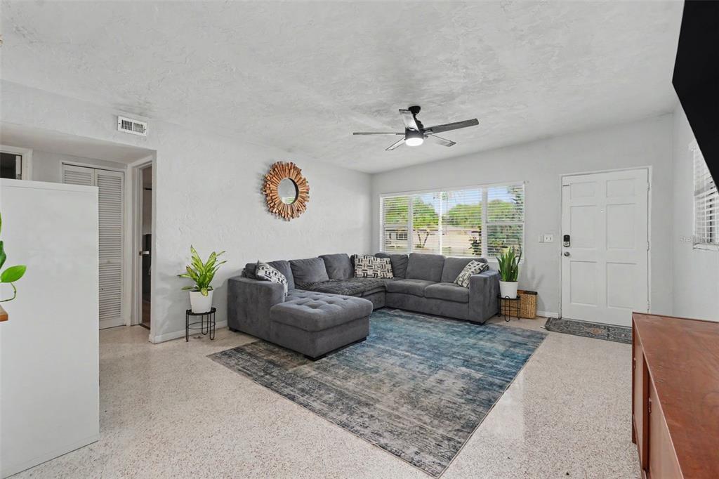 A living room features a grey sectional sofa, a blue area rug, and terrazzo flooring — 2270 NOLAN DRIVE, LARGO, FL