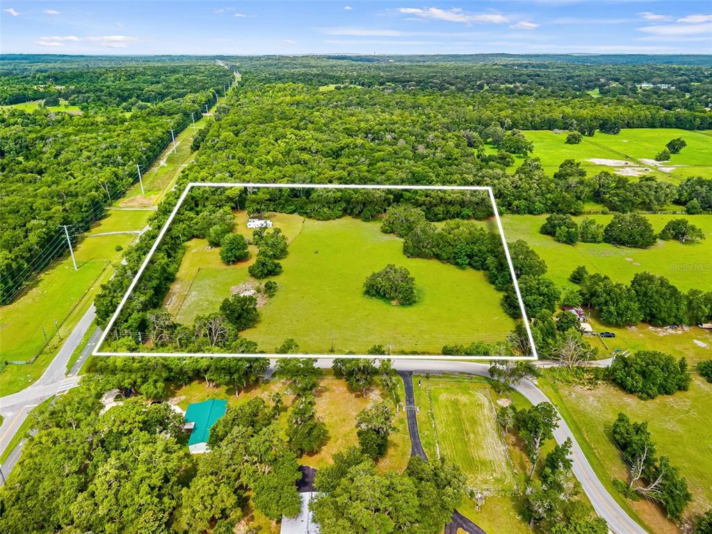 An aerial view shows a large, rectangular grassy lot outlined in white amidst wooded surroundings — 9287 WEATHERLY ROAD, BROOKSVILLE, FL