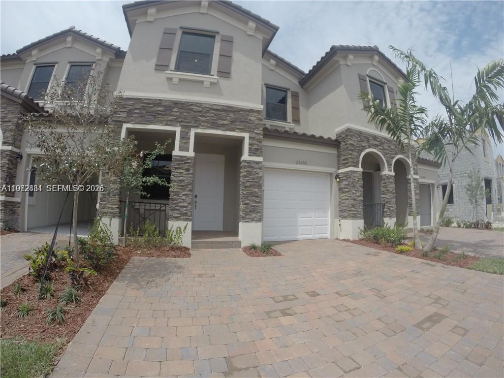 A two-story townhouse features a stone facade, a white garage door, and a paved driveway — 25356 SW 116TH AVE, Miami FL 33032, MIAMI, FL