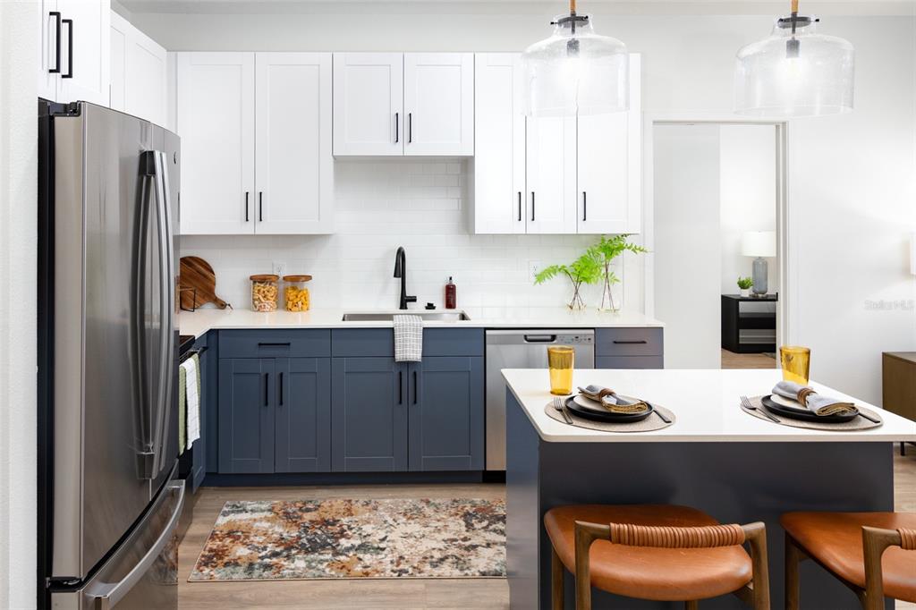 A kitchen features white upper cabinets, blue lower cabinets, a central island, and stainless appliances — 14370 FL-64 ROAD UNIT A1, BRADENTON, FL