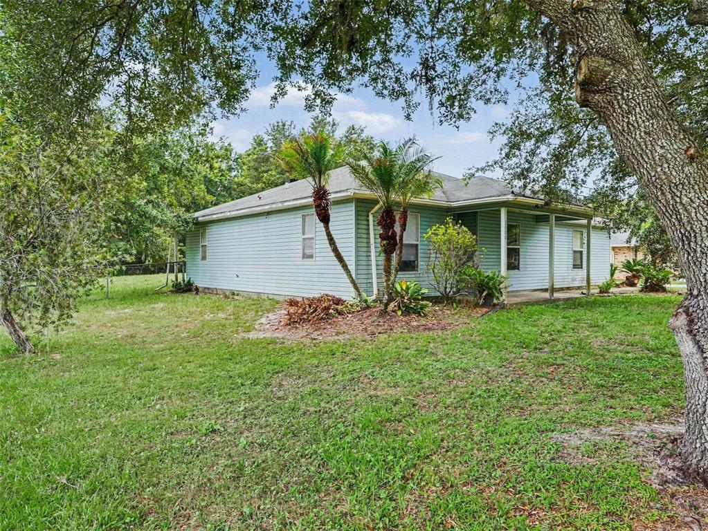 A light blue, single-story house with a covered porch sits on a grassy, tree-shaded lot — 3500 SUZETTE DRIVE, KISSIMMEE, FL