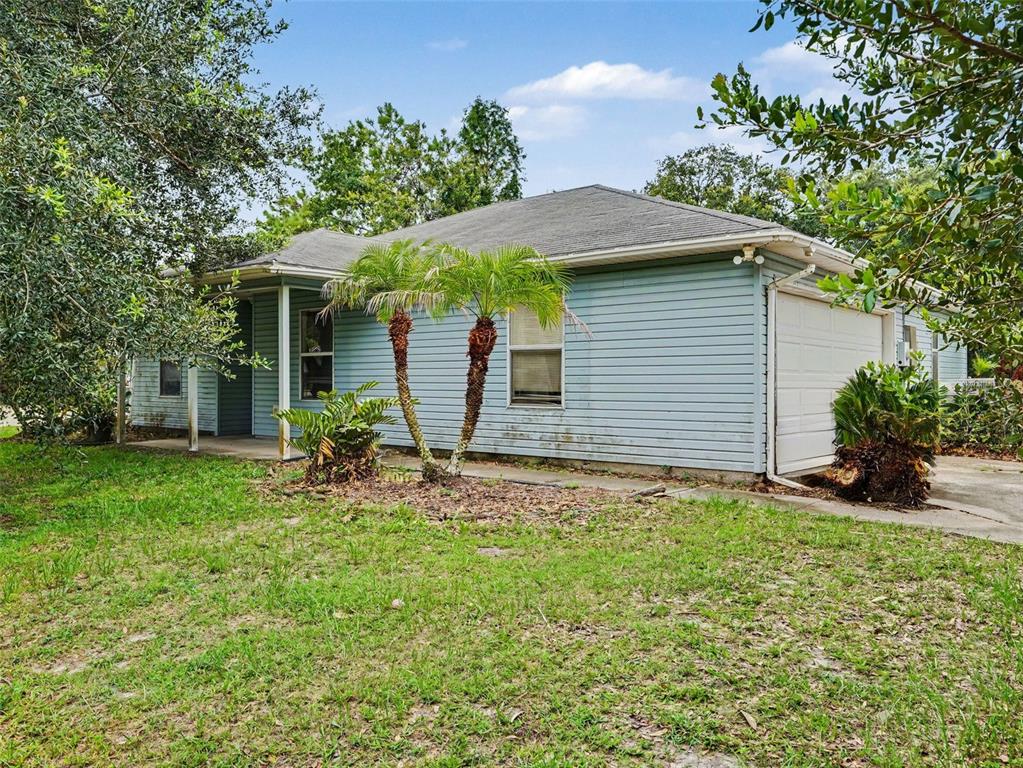 A light blue single-story house with a garage and two palm trees in the front yard — 3500 SUZETTE DRIVE, KISSIMMEE, FL