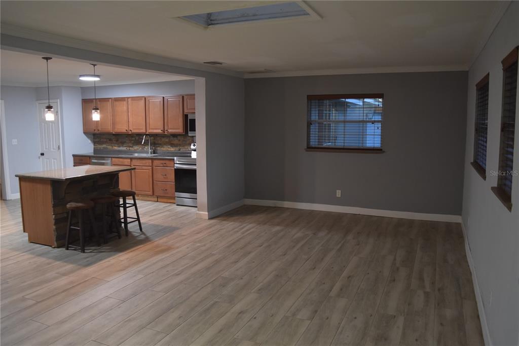 An open-concept kitchen with wood cabinets and an island overlooks a spacious living area — 1722 NW 35 STREET, OCALA, FL
