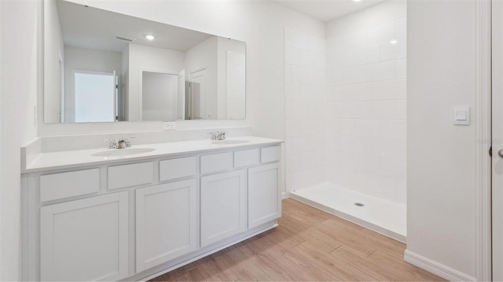 A bathroom features a double vanity with white cabinets and a walk-in tiled shower — 1348 FOUNTAIN VIEW STREET, ORMOND BEACH, FL