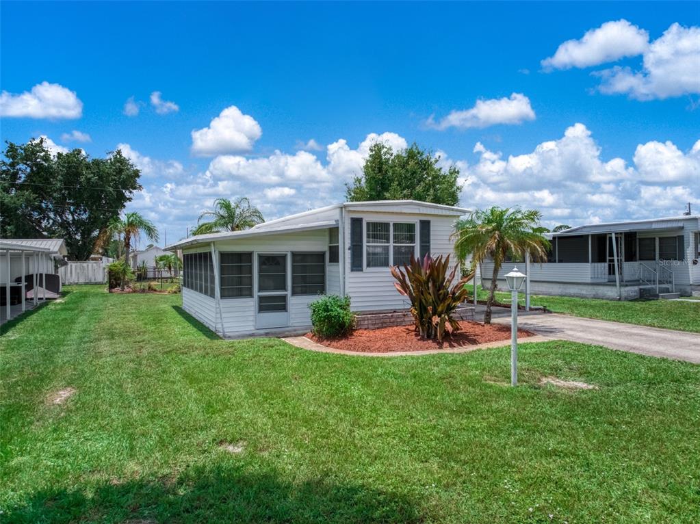 A white mobile home with a screened-in porch sits on a grassy lot — 3519 MAINE AVENUE, SEBRING, FL