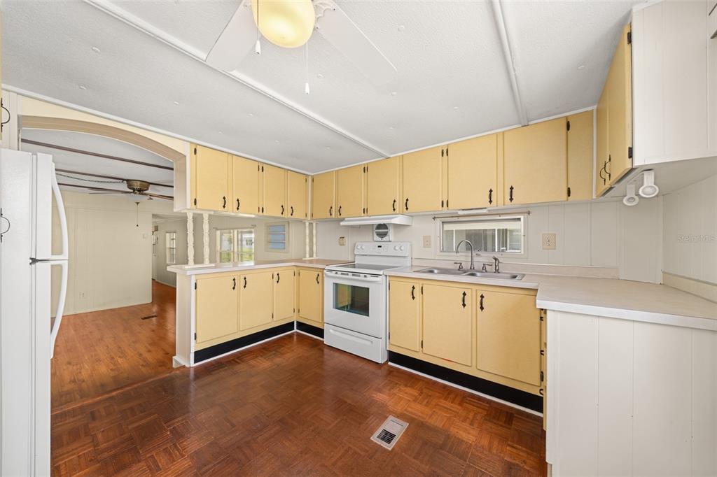 A kitchen with yellow cabinets, white appliances, and wood-look flooring — 3519 MAINE AVENUE, SEBRING, FL