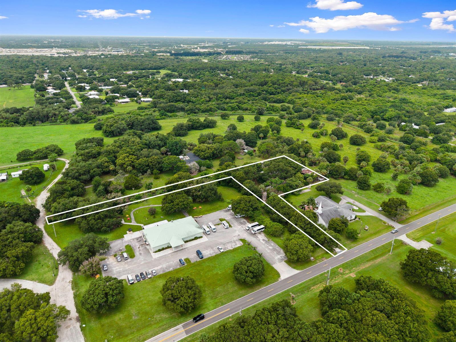 An aerial view shows a property with two buildings, a parking lot, and surrounding trees — 3603 Kirby Loop Road, Fort Pierce FL 34981, FORT PIERCE, FL