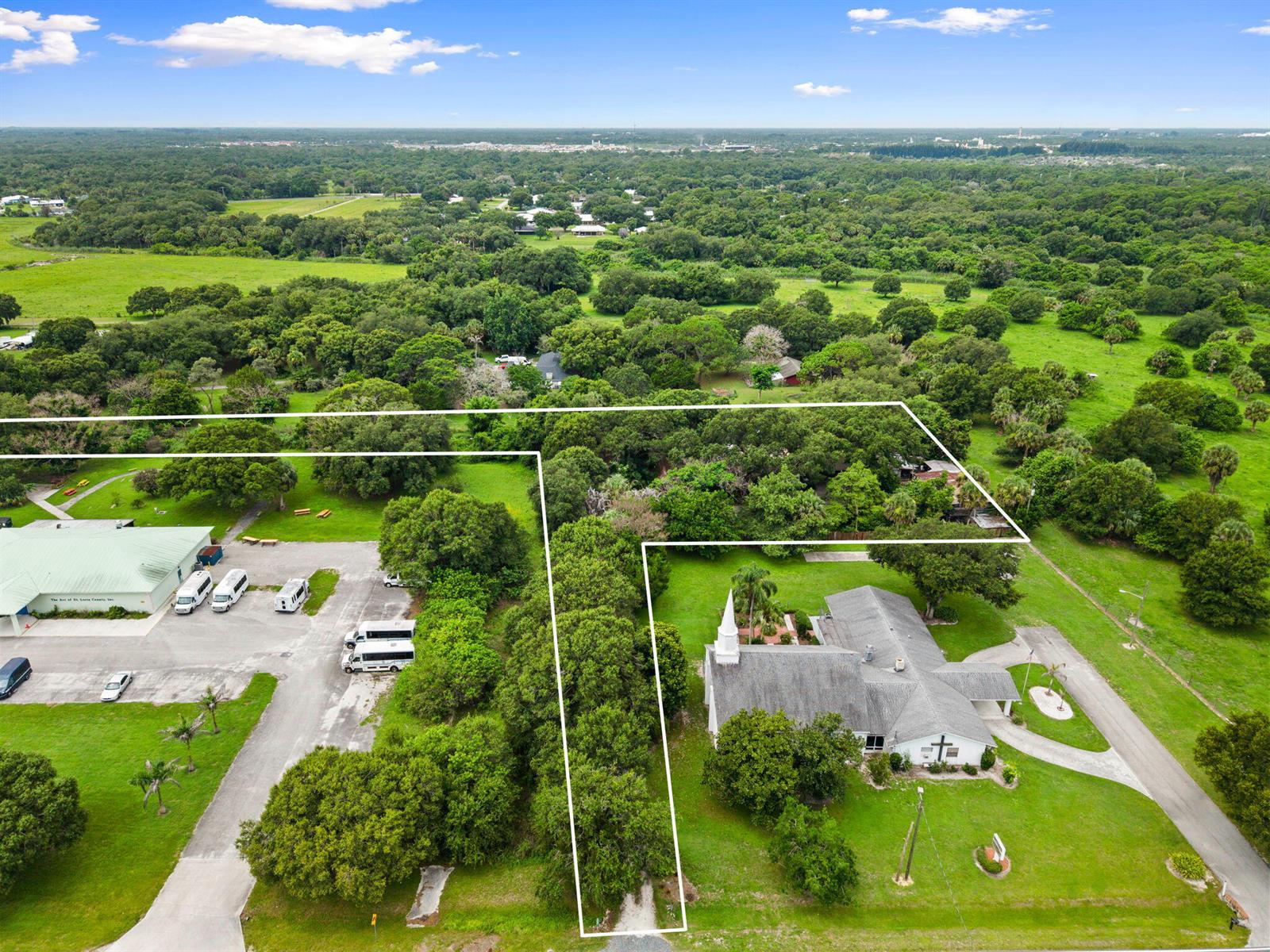 An aerial view shows a church building and a parking lot surrounded by green trees — 3603 Kirby Loop Road, Fort Pierce FL 34981, FORT PIERCE, FL