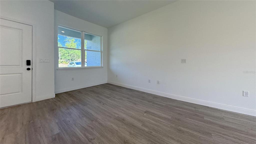 An empty room features white walls, light wood-look flooring, a window, and a white door — 6575 N GRAYTON TERRACE, CITRUS SPRINGS, FL