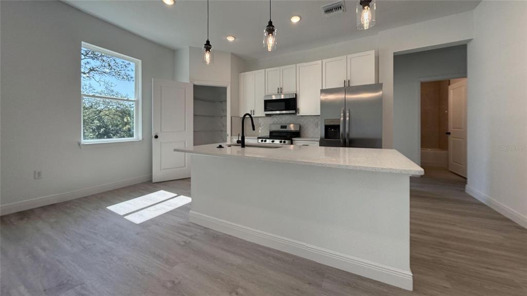A modern kitchen features white cabinets, stainless steel appliances, and a central island with seating — 6575 N GRAYTON TERRACE, CITRUS SPRINGS, FL