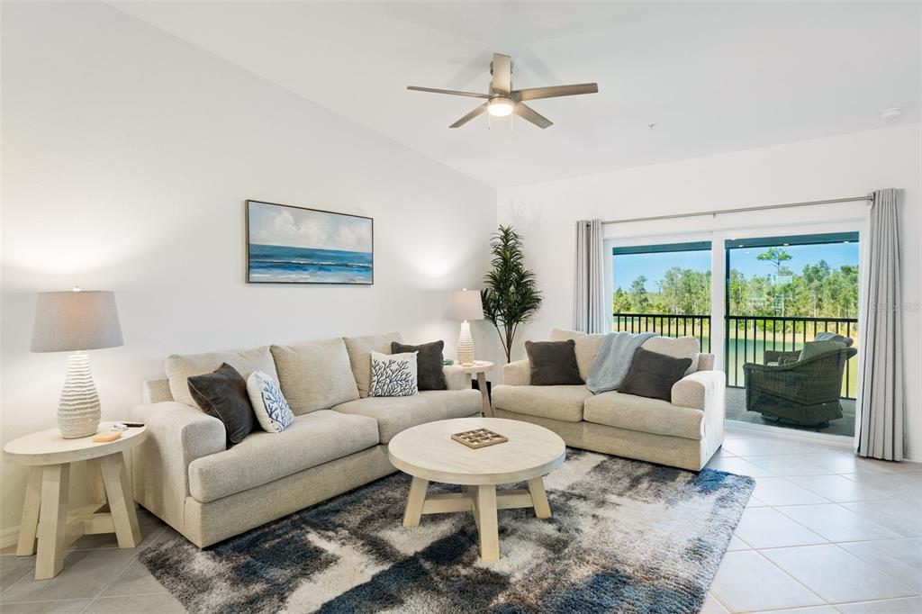 A living room features light-colored sofas, a round coffee table, and a sliding glass door — 14241 HERITAGE LANDING BOULEVARD UNIT 1827, PUNTA GORDA, FL