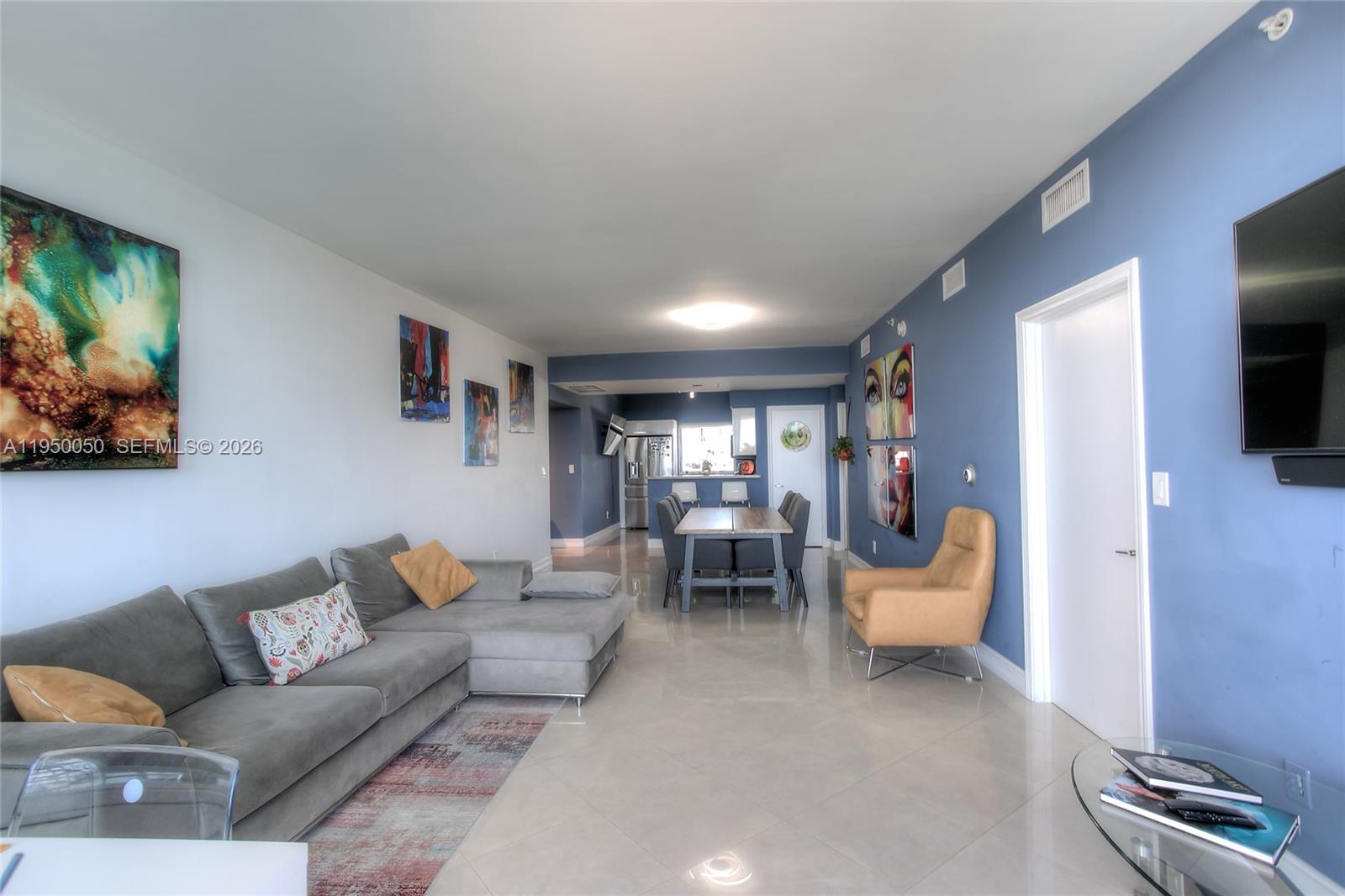 A living and dining area features gray tile floors, blue accent walls, and modern furniture — 601 NE 36th St # 710, Miami FL 33137, MIAMI, FL