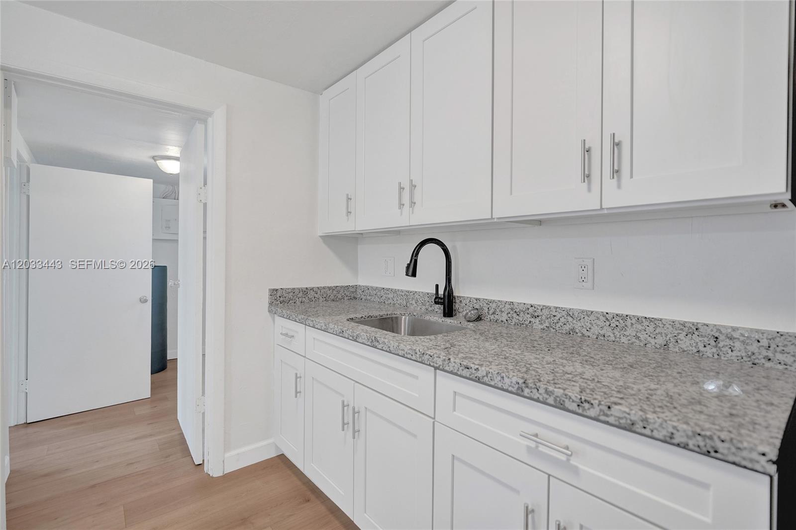 A kitchen features white shaker cabinets, granite countertops, and a black faucet — 307 NW 11th Ave, Delray Beach FL 33444, DELRAY BEACH, FL