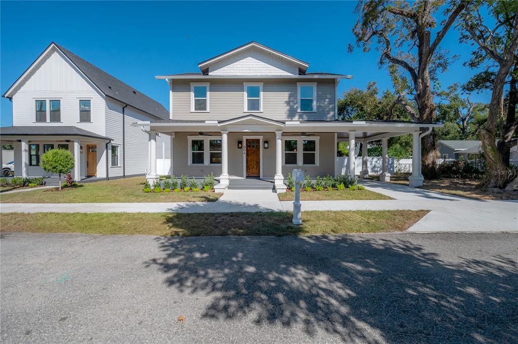 A two-story house with a covered front porch, carport, and light-colored siding — 804 E WILDER AVENUE, TAMPA, FL