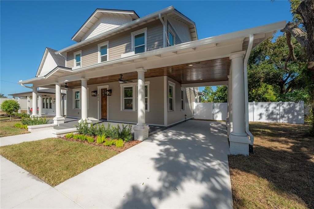 A two-story house features a covered front porch, a carport, and light-colored siding — 804 E WILDER AVENUE, TAMPA, FL