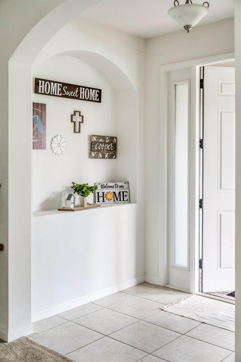 An entryway features a tiled floor, a white arched wall niche, and a glass-paneled front door — 16881 Meadows Street, Clermont FL 34714, CLERMONT, FL
