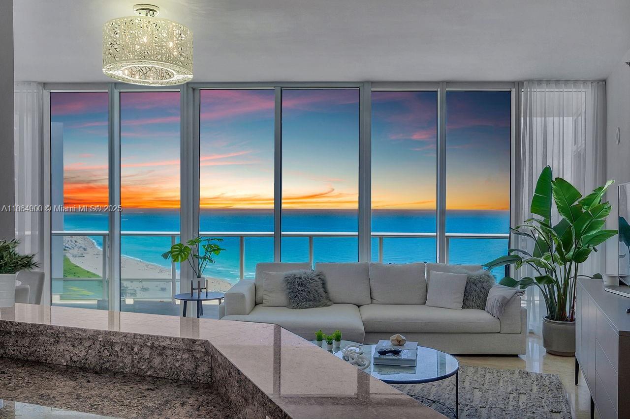 A living room features floor-to-ceiling windows with an ocean view and a modern chandelier — 100 S Pointe Dr # 2208, Miami Beach FL 33139, MIAMI BEACH, FL