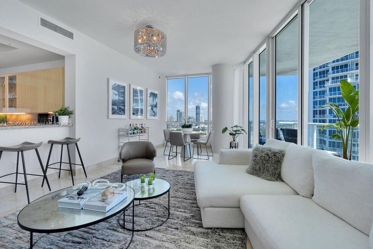 A modern living room features a white sectional sofa, glass coffee tables, and floor-to-ceiling windows — 100 S Pointe Dr # 2208, Miami Beach FL 33139, MIAMI BEACH, FL